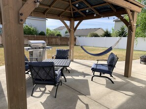 Enjoy al fresco dining and relaxation in this outdoor space with a barbecue grill, dining table, and hammock.