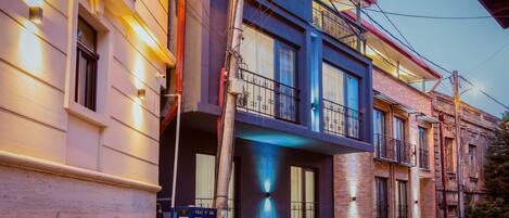 A row of multi-story buildings with balconies, a police box, and a street lamp.