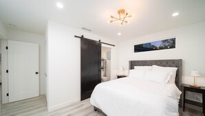 Un dormitorio con una cama grande, una puerta corredera, una lámpara de techo y una ventana.