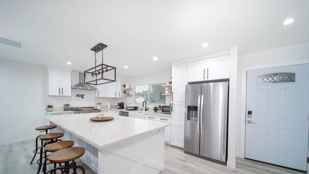 Una cocina moderna con una isla grande, electrodomésticos de acero inoxidable y taburetes de bar.