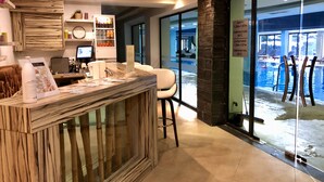 A reception desk with a wooden design, a computer, and a sign indicating pool depth and temperature. - Luxury 2BR Penthouse in an elegant hotel with lavish SPA & Heated Swimming Pool (Bansko)
