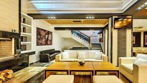 A modern living room with a wooden coffee table, white sofas, and a staircase leading to a bar named 'BAR Alexandra'. - Luxury 2BR Penthouse in an elegant hotel with lavish SPA & Heated Swimming Pool (Bansko)