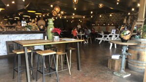 Una zona de bar con taburetes, una barra y luces colgantes.
