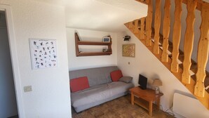 A cozy living area with a sofa, a small table with a lamp, and a wooden staircase. - Aussois le bon choix - Apartment at the foot of the pistes, south facing, sleeps 5 (Aussois)