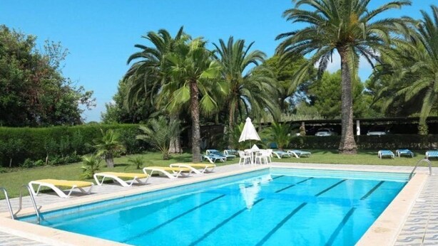 A swimming pool with lounge chairs and palm trees. - Chalet located on a wooded park of 8000m ² with large community pool, . (Vilafortuny)