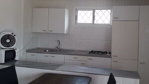 A modern kitchen with white cabinets, a microwave, a sink, and a window above the countertop. - Chalet located on a wooded park of 8000m ² with large community pool, . (Vilafortuny)