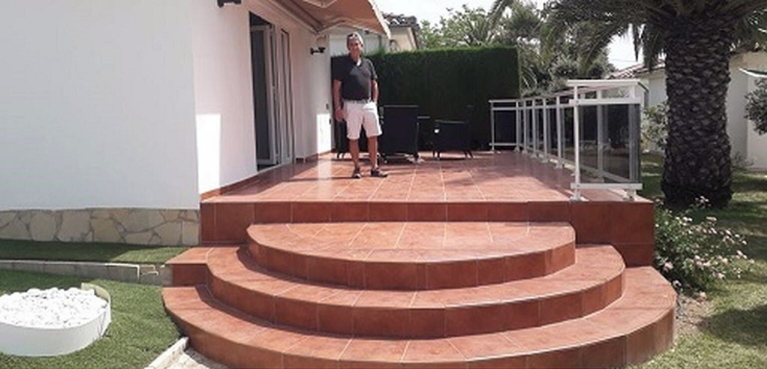 A man standing on a set of outdoor stairs leading to a house entrance.