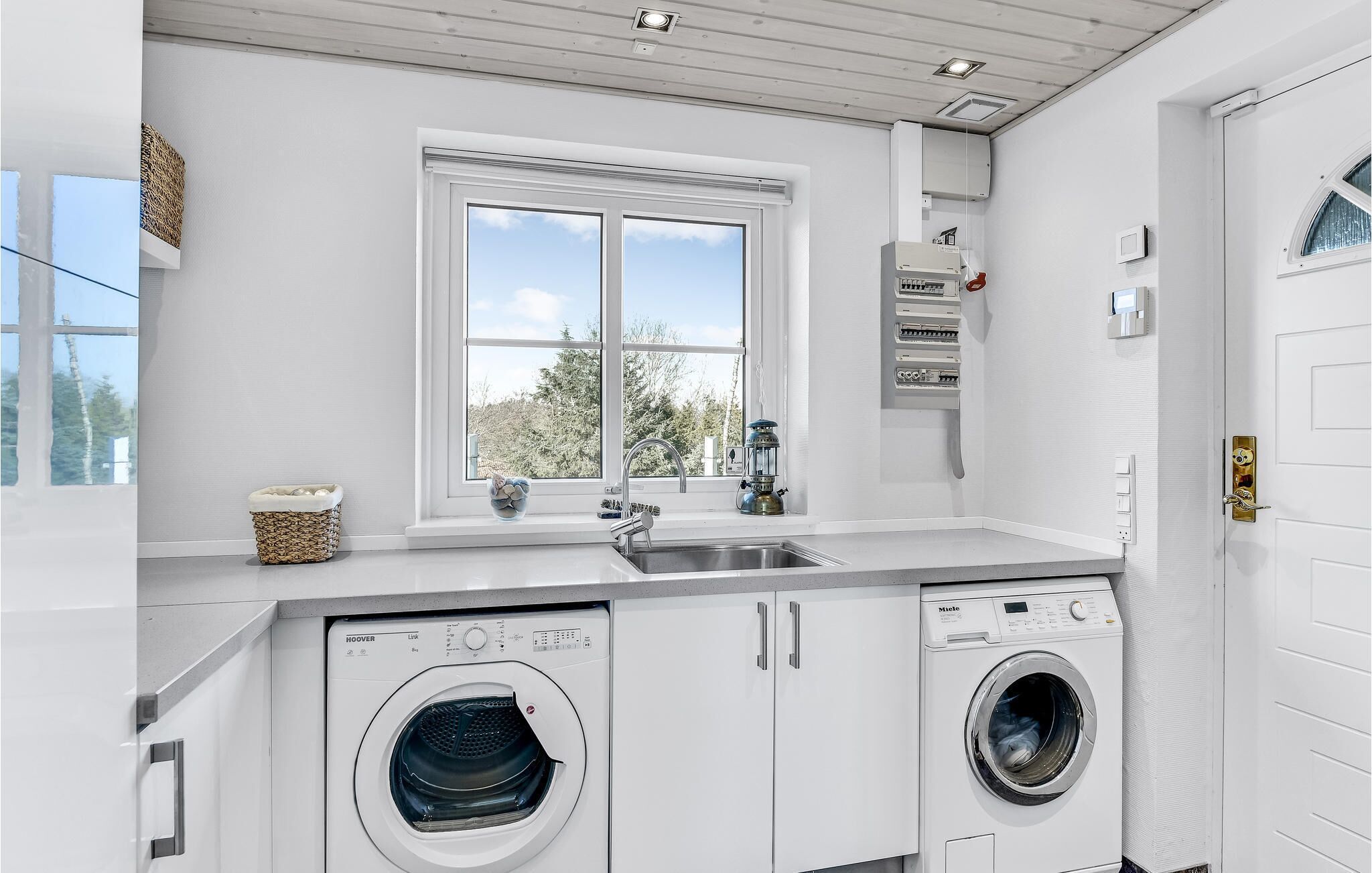A laundry room with two front-loading washers, a window, and a sink.