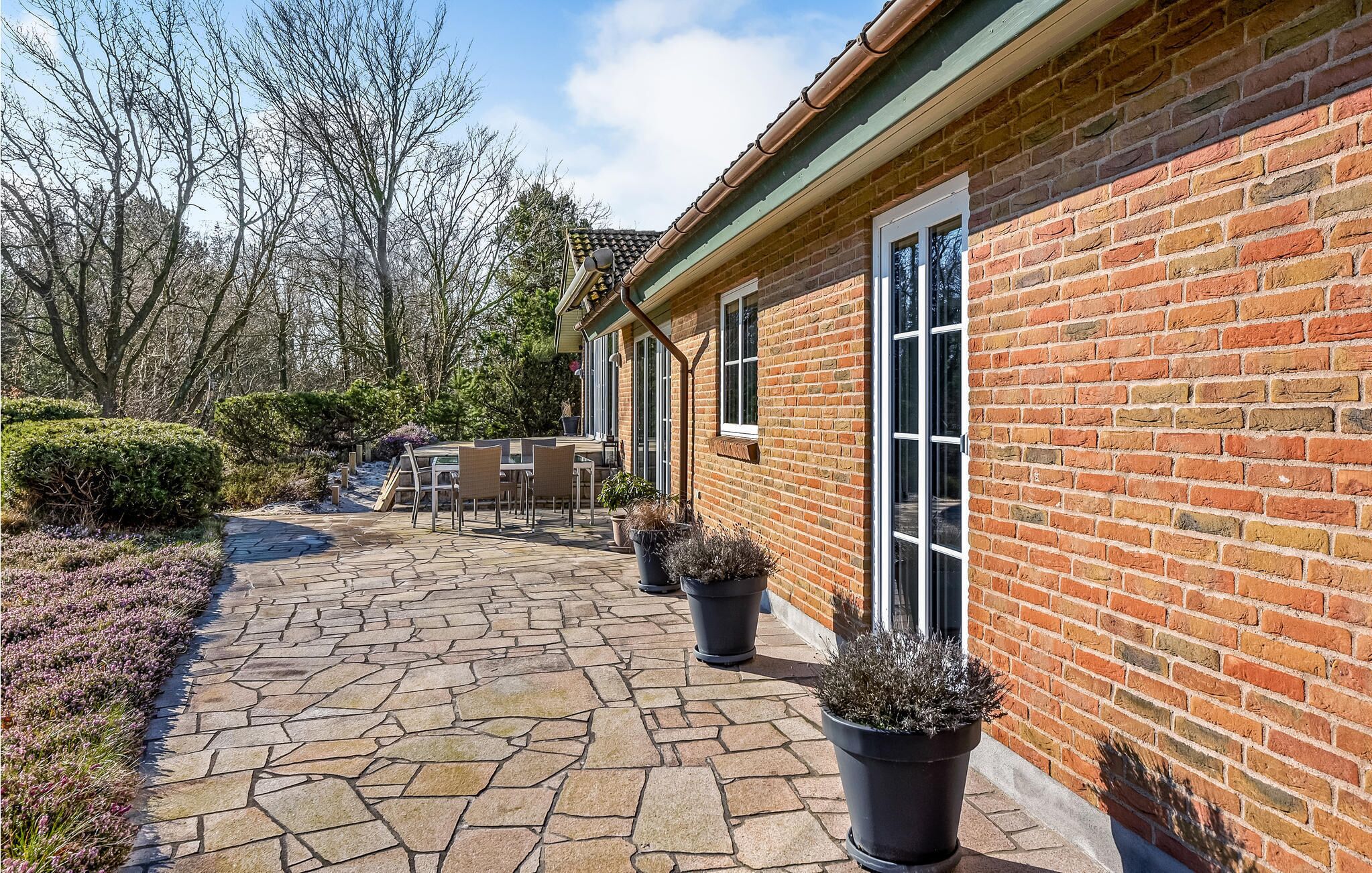 A brick house with a stone patio, outdoor furniture, and potted plants.