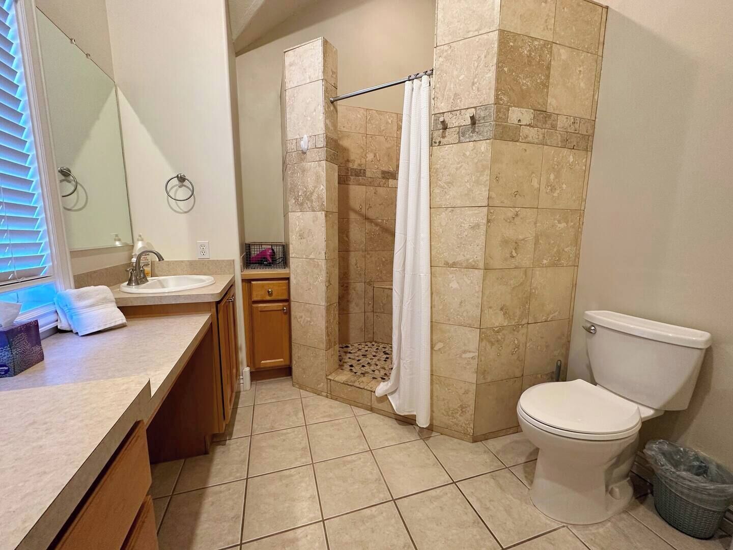Une salle de bain équipée d’une douche, de toilettes, d’un lavabo et d’un miroir.