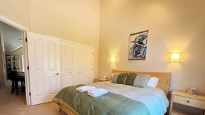Ein Schlafzimmer mit einem Bett, einem Nachttisch, einer Wandlampe und einer Tür zu einem anderen Raum.