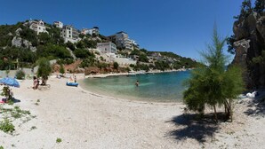 A beach with clear turquoise water, white sand, and buildings on a hillside. - 2 bedroom amazing apartment in Vinisce (Vinisce)