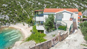 A coastal property with a beach, a stone wall, and a house with a red-tiled roof. - 2 bedroom amazing apartment in Vinisce (Vinisce)