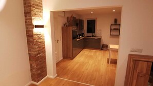 A modern kitchen with wooden cabinets and a brick accent wall. - House on the terp, vacation apartment#1 ground floor (Pogum)