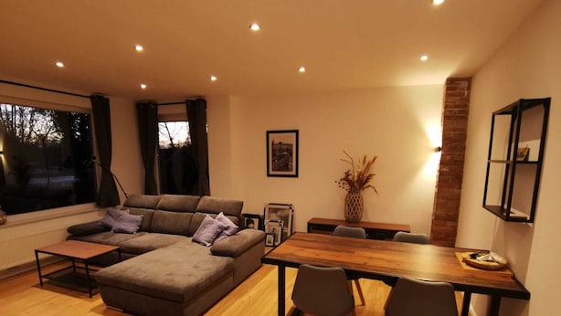 A modern living room with a sectional sofa, a wooden dining table, and a fireplace. - House on the terp, vacation apartment#1 ground floor (Pogum)