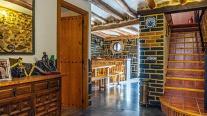 Un interior rústico con vigas de madera a la vista, una pared de piedra y una escalera de ladrillo.