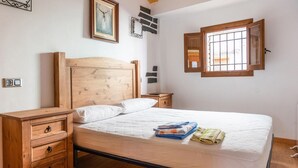 Un dormitorio con una cama de madera, una mesita de noche, una cómoda y un ventanal con vistas.