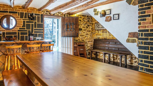Un interior rústico con barra de madera, paredes de piedra y vigas a la vista.