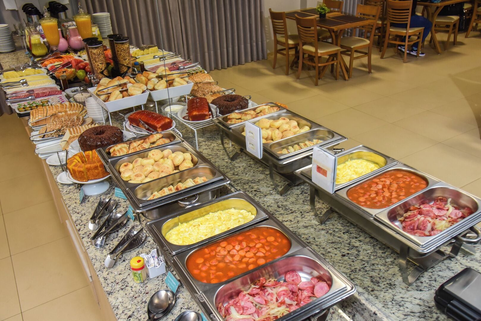 Un bufé con diversas opciones de comida, incluyendo frutas, pasteles y carnes.