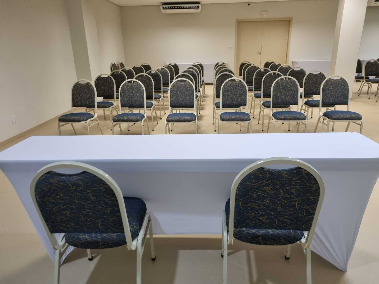 A conference room with rows of chairs and a long table, equipped with an air conditioning unit.