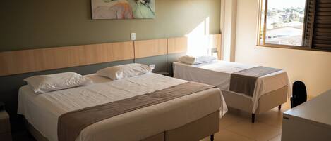 Habitación de hotel con dos camas, un escritorio, una ventana y un cuadro en la pared.