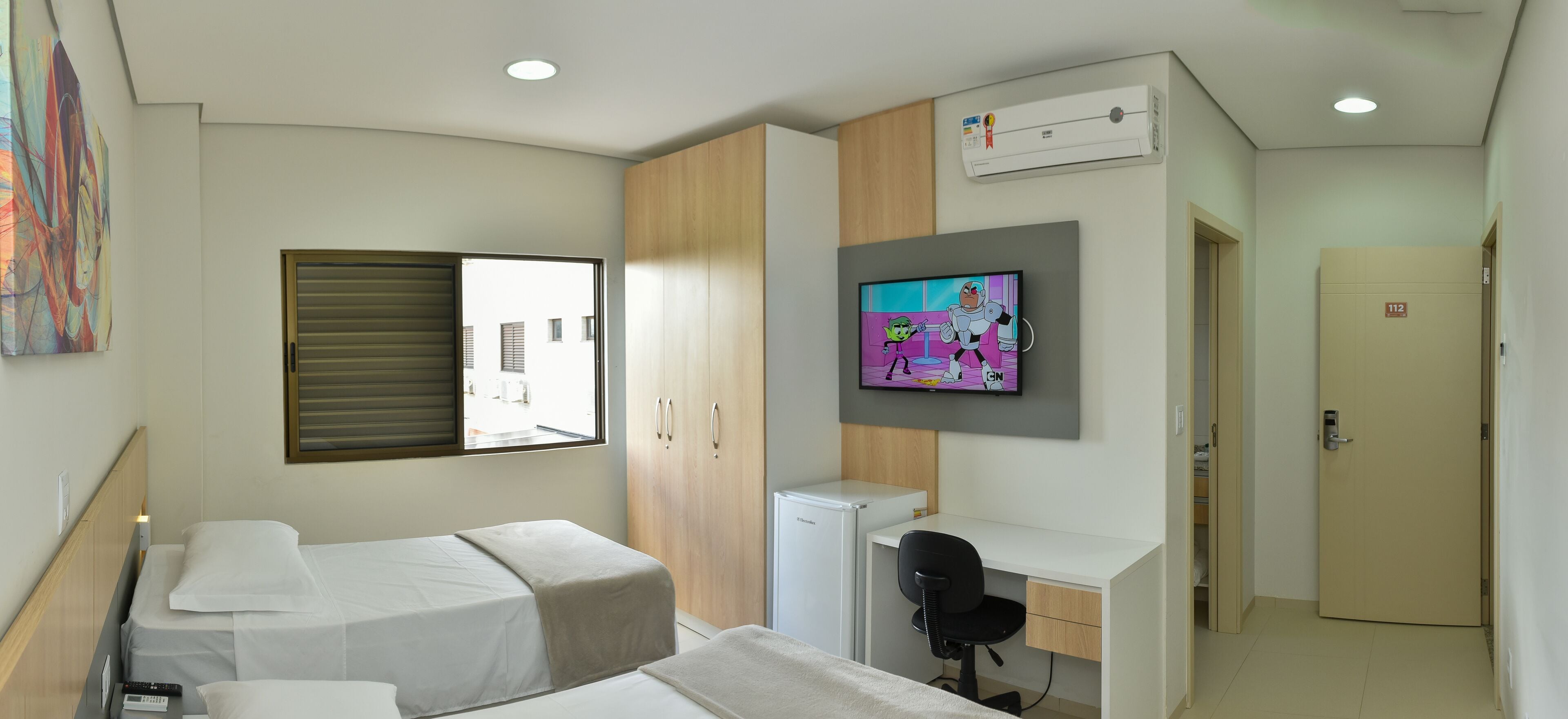 Una habitación de hotel con dos camas, un escritorio, un televisor y un aire acondicionado.