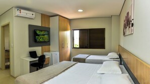 Una habitación de hotel con dos camas, un escritorio con una computadora portátil, un televisor y una ventana con persianas.