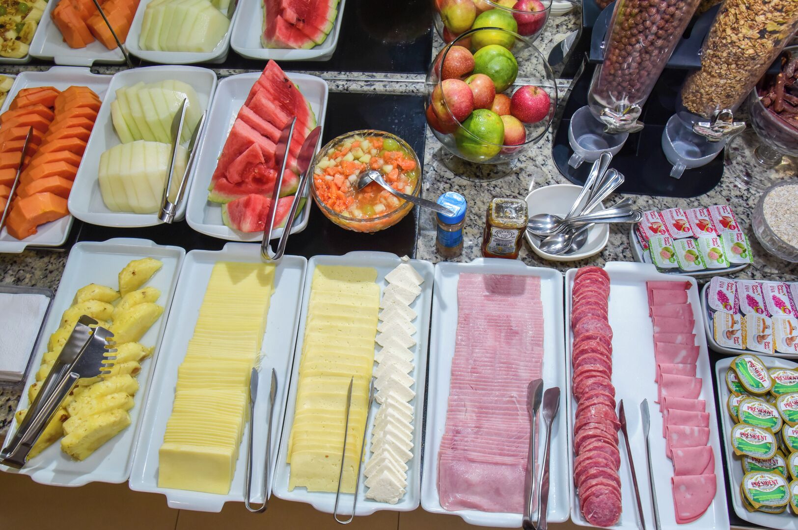A buffet with various food items including fruits, vegetables, cheeses, and meats.