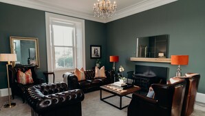 Een woonkamer met een open haard, lederen meubels en een groot raam.