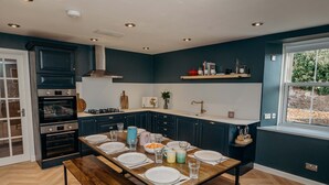 Een moderne keuken met donkere kastjes, een inbouwoven en een eettafel voor vier personen.