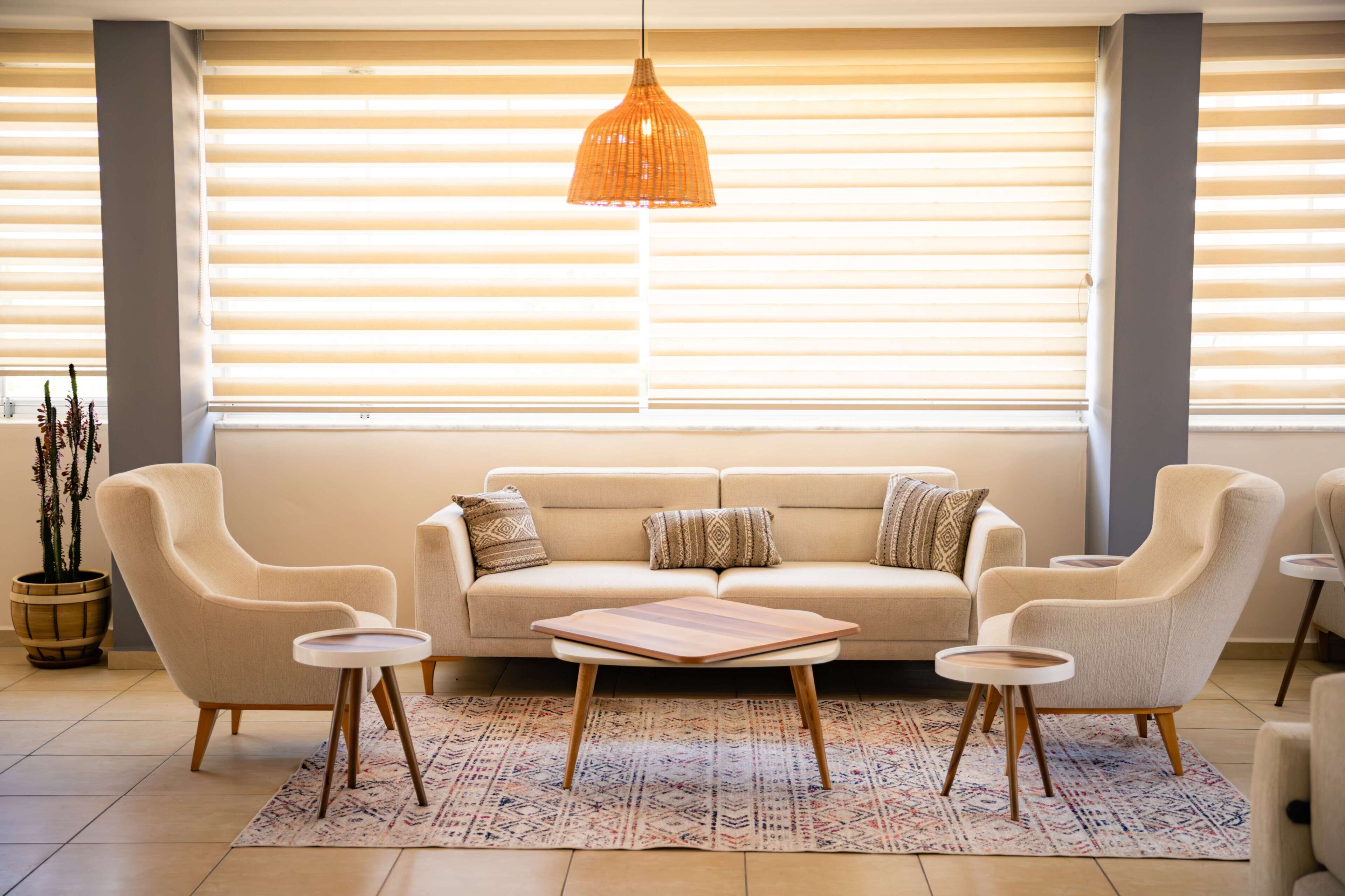 A modern living room with a sofa, two armchairs, a coffee table, and a hanging light fixture.