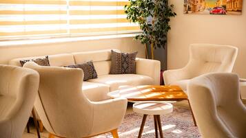 A living room with a sofa, two armchairs, a coffee table, and a plant.