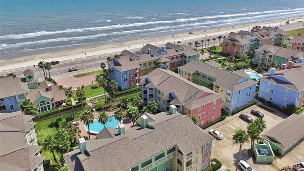 A coastal residential area with colorful houses, a beach, and a swimming pool. - <br>The Dolphin Poolside at The Dawn. (Galveston)