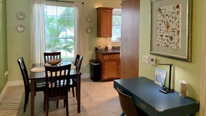 A dining area with a table and chairs, a kitchen area with cabinets, and a framed picture on the wall. - <br>The Dolphin Poolside at The Dawn. (Galveston)