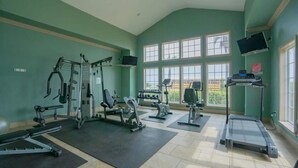 A gym with various exercise equipment, large windows, and a tiled floor. - <br>The Dolphin Poolside at The Dawn. (Galveston)