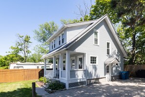 A two-story house with a porch, a fenced yard, and a wooden deck. - The Coach House (Lorain)