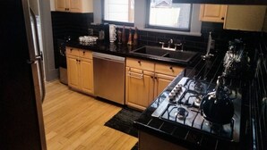 A kitchen with wooden cabinets, a black countertop, a stove, and a dishwasher. - The Le Chic Bungalow (Decatur)