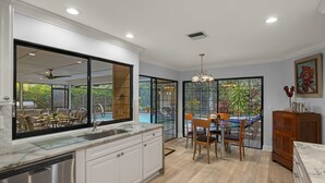 Una cocina moderna con una isla grande, un comedor con vistas al exterior y un armario de madera.