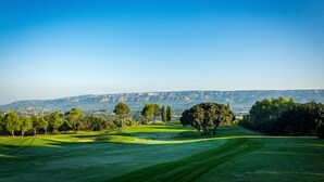 Um campo de golfe com vista ampla para montanhas e árvores ao longe.