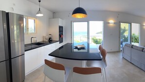 A modern kitchen with a central island, stainless steel appliances, and a view of the sea. - spacious appartment facing the sea with private garden jaccuzi and plancha grill (Saint Martin)