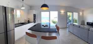 A modern kitchen with a central island, stainless steel appliances, and a view of the sea. - spacious appartment facing the sea with private garden jaccuzi and plancha grill (Saint Martin)