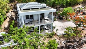 A modern two-story house with a flat roof, large windows, and a balcony. - spacious appartment facing the sea with private garden jaccuzi and plancha grill (Saint Martin)