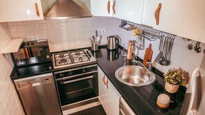 Una cocina moderna con electrodomésticos de acero inoxidable, lavavajillas, horno y pileta.