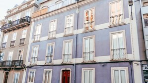 Un edificio de varios pisos con balcones, una puerta roja y numerosas ventanas.