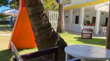 Relax in a serene outdoor space with a palm tree, table, and bench, surrounded by a well-manicured lawn and a fence.