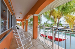 A covered balcony with white chairs, a view of a marina with boats, and palm trees. - Key Colony Beach Rentals, Fl, Boat Dock, Sleep 10 - 5 Bedrooms, Waterfront, Pool (Key Colony Beach)
