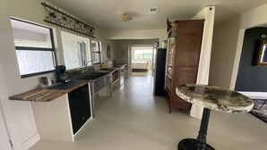 A modern kitchen with a built-in dishwasher, a coffee maker, and a sink. There is a dining table with a unique marble top.