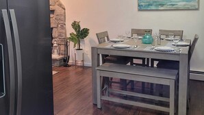 Una cocina moderna con refrigerador integrado, mesa de comedor de madera para cuatro comensales y una pared de acento de piedra.