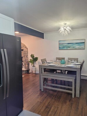 Eine moderne Küche mit Einbaukühlschrank, einem Holzespeisetisch für vier Personen und einer Wand mit Steinverkleidung.