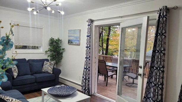 Un salón con un sofá azul oscuro, una mesa de centro blanca y vistas a un patio con mobiliario exterior.